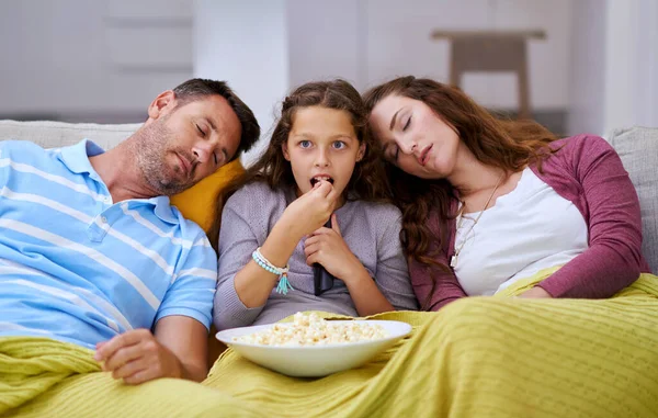 La serata film e 'durata troppo per i suoi genitori. Ritagliato colpo di una giovane ragazza guardando un film mentre entrambi i suoi genitori dormono su entrambi i lati di lei. — Foto Stock