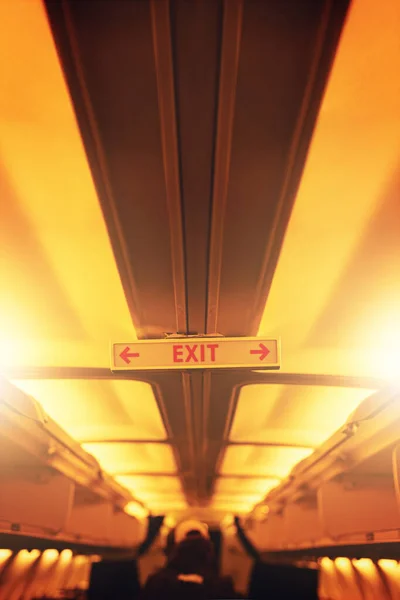 Atención pasajeros Por favor tome nota de las salidas de emergencia. Tiro de una señal de salida dentro de un avión. —  Fotos de Stock