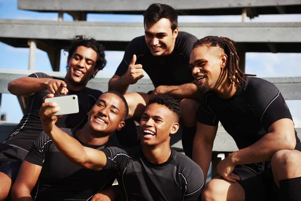 Het is geen halve tijd voordat je een selfie neemt. Een foto van een jonge man die een selfie maakte met zijn teamgenoten bij een rugbywedstrijd.. — Stockfoto