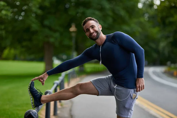 Ikke glem å tøye ut. Hengte portretter av en kjekk ung løper som varmer opp før treningen.. – stockfoto