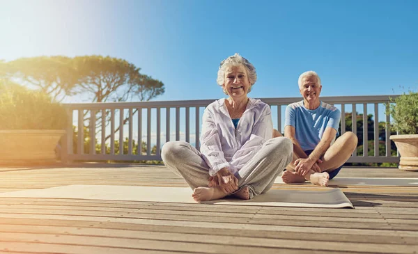 Mantener una mente y un cuerpo sanos. Toma de una pareja de ancianos haciendo yoga juntos en su patio exterior. —  Fotos de Stock