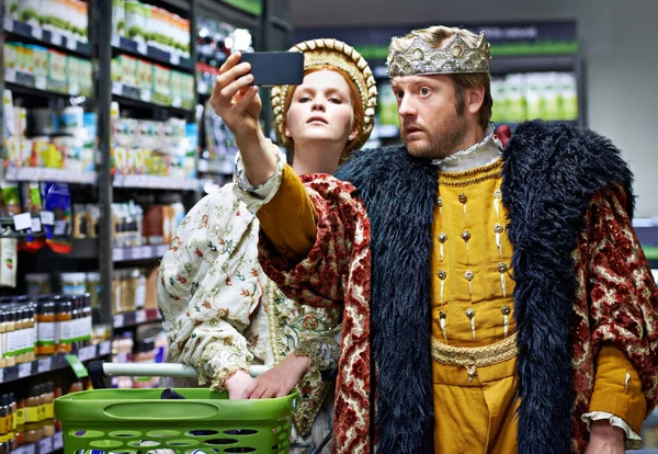 No demasiado real para ir de compras. Un rey y una reina tomando una selfie en su supermercado local. —  Fotos de Stock