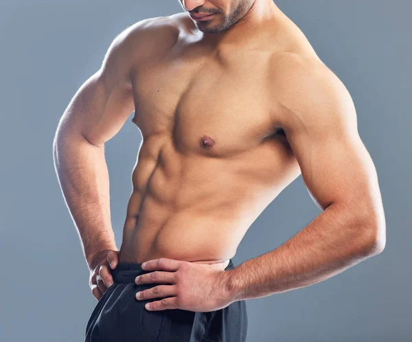 Це точно не середнє тіло. Студійний знімок м'язистого молодого чоловіка, що позує на сірому фоні . — стокове фото