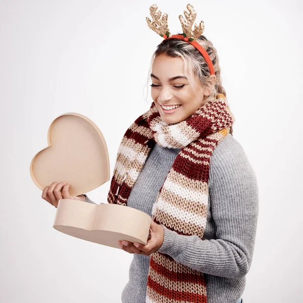 Що в коробці. Студійний знімок привабливої молодої жінки, що відкриває серцеподібну коробку, одягнену в різдвяний одяг . — стокове фото
