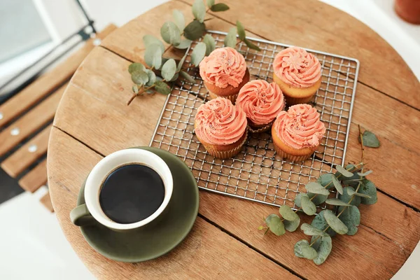 Agencé soigneusement et blog prêt. Plan grand angle de cupcakes fraîchement cuits sur un plateau en métal et une tasse de café sur une table à l'intérieur. — Photo