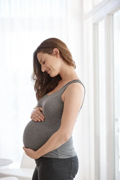 Δείχνοντας στο αγέννητο μωρό της λίγη αγάπη. Τραβηγμένη φωτογραφία μιας νεαρής εγκύου που στέκεται στο σπίτι της.. — Φωτογραφία Αρχείου