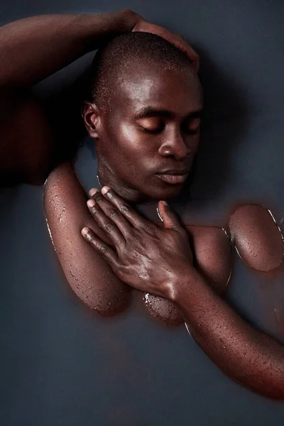 暗闇を克服するために時にはそれに身を浸す必要があります。暗い水で満たされた風呂に浸かったハンサムな若い男のショット. — ストック写真