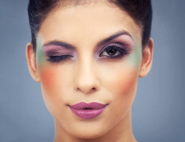 Flirting with many colours. Headshot of a beautiful young woman wearing colorful makeup. Royalty Free Stock Images