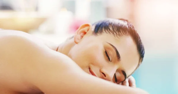 Lassen Sie einfach den Stress weg. Aufnahme einer jungen Frau, die sich in einem Wellnessbereich auf einem Massagebett entspannt. — Stockfoto