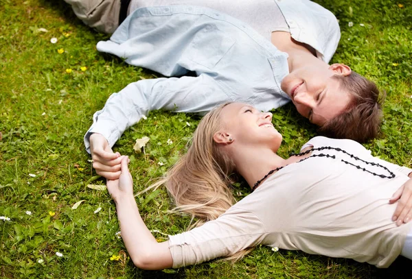Momentos de verão. Bonito jovem casal deitado juntos na grama fora. — Fotografia de Stock
