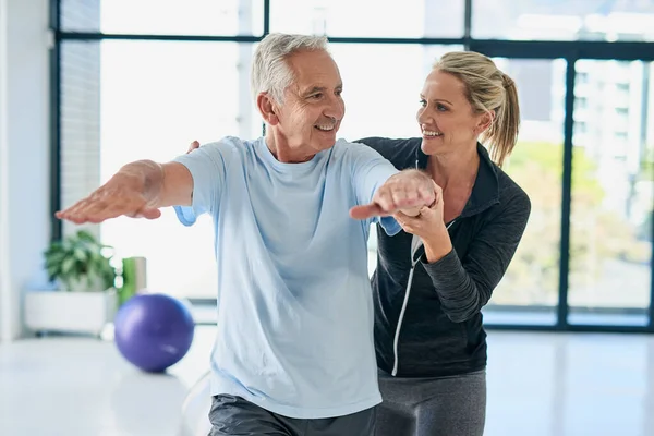 Mantente flexible, lo estás haciendo bien. Recorte de un amigable fisioterapeuta femenino ayudando a su paciente mayor con sus ejercicios. — Foto de Stock