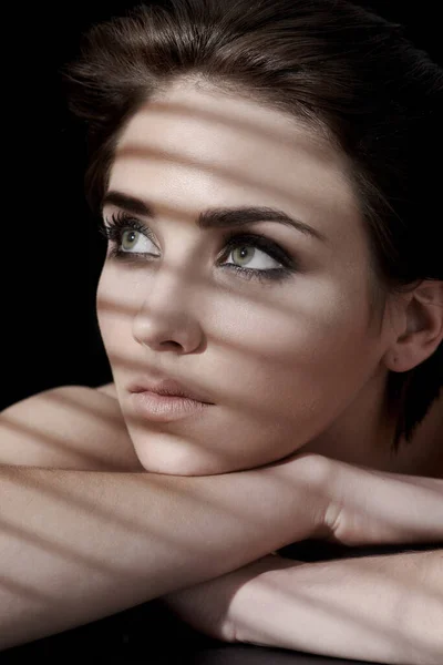 A contemplar a beleza. Uma jovem mulher com pele impecável e cabelo escuro olhando para trás contra um fundo escuro. — Fotografia de Stock