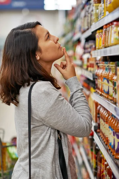 Tüm seçeneklerini göz önünde bulundurursak. Markette eşyalar arayan genç bir kadının kırpılmış görüntüsü.. — Stok fotoğraf