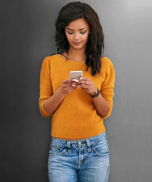 Blijf in het sociale circuit met moderne technologie. Studio shot van een jonge vrouw met behulp van haar telefoon tegen een grijze achtergrond. — Stockfoto