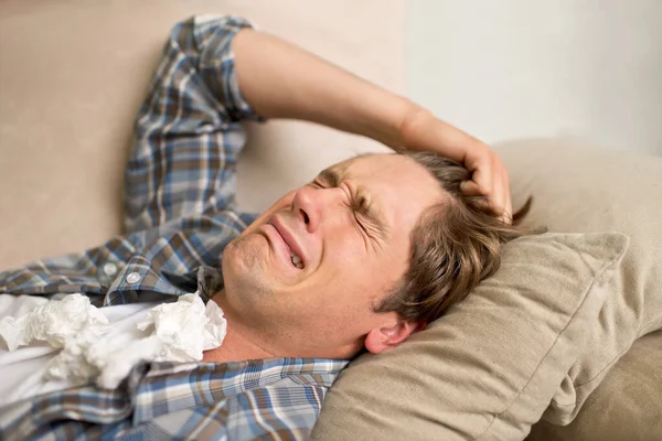 Egy rossz szakítással kell megbirkóznom. Egy fiatal férfi sír, miközben a kanapén fekszik zsebkendővel.. — Stock Fotó