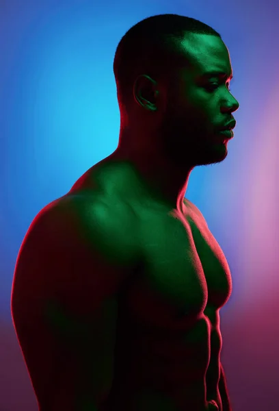 Challenges only make you stronger. Studio shot of a man posing shirtless against a neon background. — ストック写真