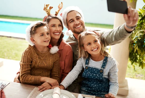 Estavam sempre prontos para uma selfie de Natal. Tiro cortado de uma família de quatro tomando uma selfie juntos no dia de Natal. — Fotografia de Stock