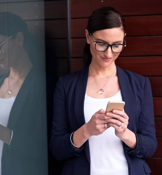 Mi oficina en la palma de mi mano. Foto de una mujer de negocios feliz usando su teléfono inteligente junto a una ventana en la oficina. —  Fotos de Stock