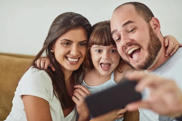 Super blij om tijd door te brengen met de familie. Shot van een moeder en vader die selfies samen met hun jonge dochter thuis. — Stockfoto