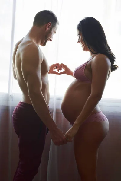 İki kalp, tek yürek. Yakışıklı bir delikanlının hamile karısını yatak odasında severkenki görüntüsü.. — Stok fotoğraf