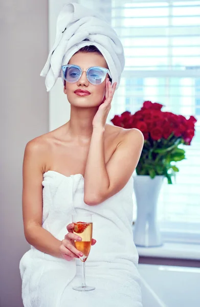 Entspannen wie ein Royal. Aufnahme einer attraktiven jungen Frau, die ein Glas Champagner genießt, während sie durch ihre morgendliche Routine geht. — Stockfoto