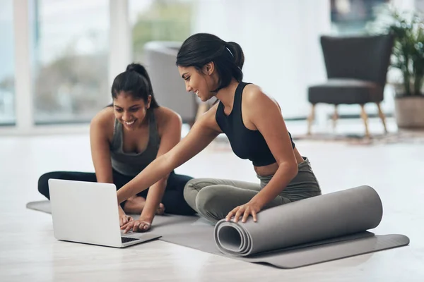 Lets start our virtual session. Shot of two young women using a laptop while working out at home. — ストック写真