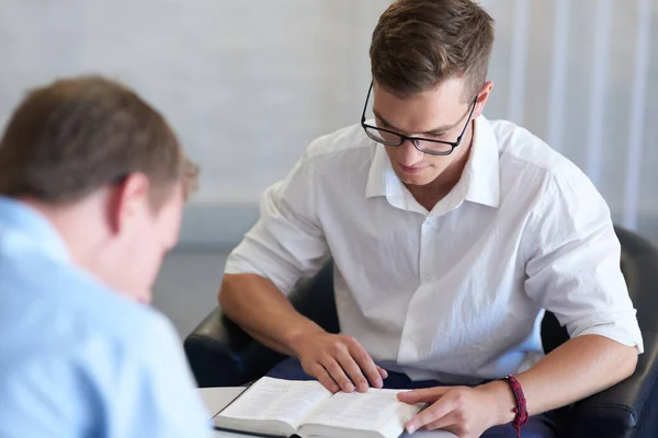 La creencia es un factor importante en cualquier aspecto de la vida. Fotografía de dos jóvenes empresarios leyendo sus biblias en el trabajo. — Foto de Stock