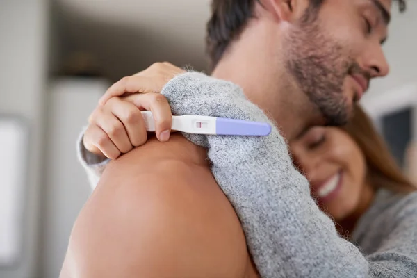 Su sueño finalmente se hizo realidad. Foto de una feliz pareja joven abrazándose después de hacerse una prueba de embarazo en casa. — Foto de Stock