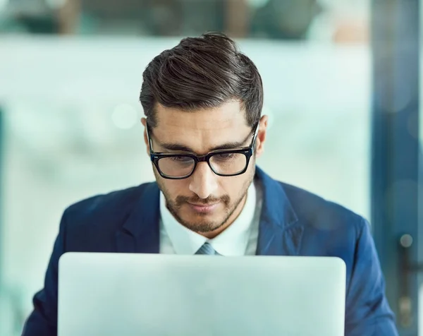 Bedrijfsfocus. Opname van een gefocuste leidinggevende in een bril werkend op een laptop in een kantoor. — Stockfoto