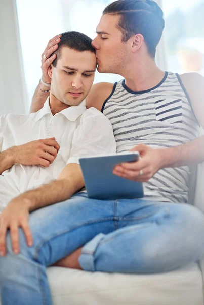 Time together is always a good time. Shot of an affectionate gay couple using a digital tablet while relaxing on the sofa at home. — Stock Photo, Image