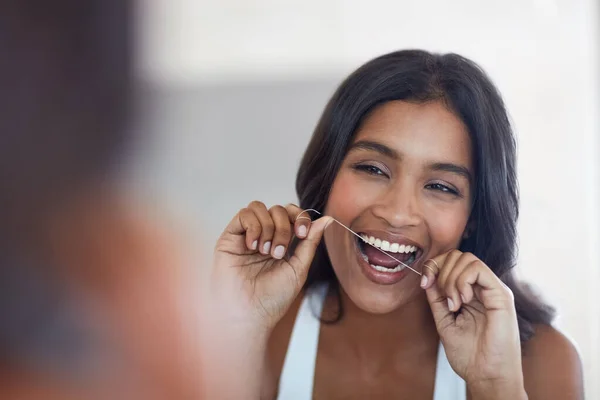 Dişlerin sağlığın hakkında çok şey söylüyor. Çekici ve mutlu bir genç kadının evdeki tuvalette dişlerini fırçalarkenki görüntüsü.. — Stok fotoğraf