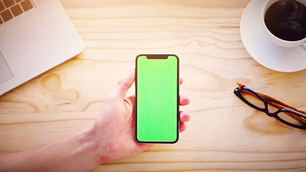 Du kan strømme hvor som helst, når som helst. Høyvinklet bilde av en ugjenkjennelig mann med en smarttelefon som viser en kromnøkkel på skjermen i et kontormiljø. – stockfoto