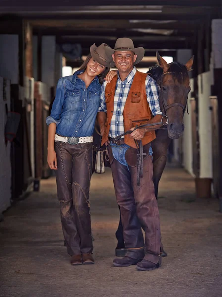 Livet på ranchen. Skjuten av en cowboy och cowgirl leder en häst ut ur ett stall. — Stockfoto