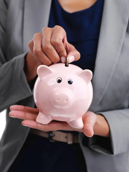 A veces un poco va muy lejos. Fotografía recortada de una mujer de negocios poniendo una moneda en su hucha. — Foto de Stock