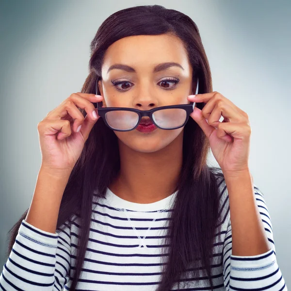Comprobando si hay suciedad en sus gafas. Foto de una joven posando sobre un fondo gris. —  Fotos de Stock