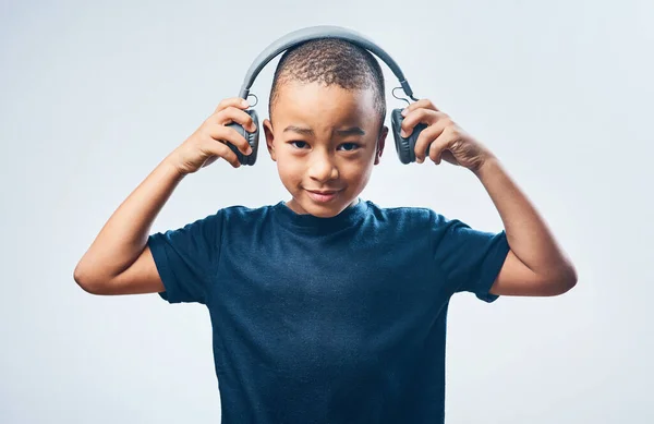 Quand je serai grand, je veux être DJ. Plan studio d'un petit garçon mignon utilisant des écouteurs sur un fond gris. — Photo