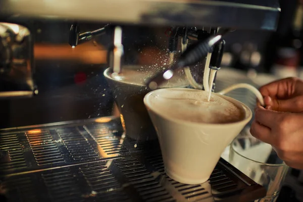 Csak egy csipetnyi tej. Egy felismerhetetlen személy közelsége, aki forró tejet önt egy csésze kávéba egy étteremben napközben.. — Stock Fotó