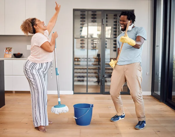 Convirtamos las tareas en una fiesta de baile. Fotografía de una joven pareja cantando y bailando mientras limpia en casa. —  Fotos de Stock
