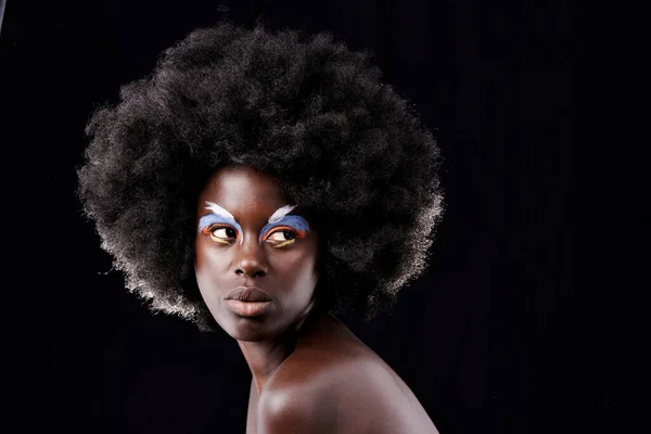 Merészen más. Stúdió lövés egy gyönyörű fiatal modell visel színes szem smink pózol ellen fekete háttér. — Stock Fotó