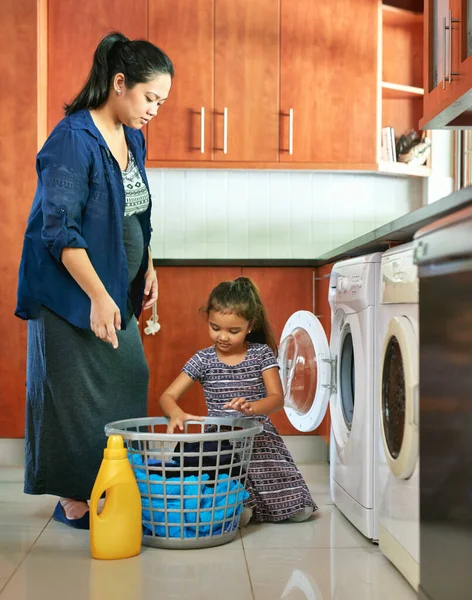 Mamme, piccolo aiutante. Girato di una madre incinta e figlia utilizzando una lavatrice a casa. — Foto Stock