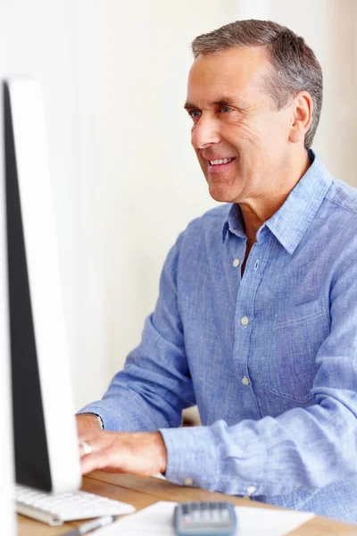 Χαμογελώντας ώριμος άνθρωπος υπολογίζοντας τα έξοδα χρησιμοποιώντας υπολογιστή. Πορτρέτο ενός χαμογελαστού ώριμου άνδρα που υπολογίζει τα έξοδα χρησιμοποιώντας υπολογιστή. — Φωτογραφία Αρχείου
