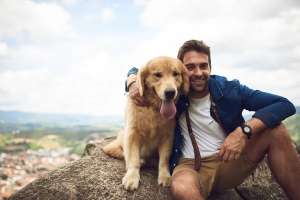 Buradan manzara çok güzel görünüyor. Yakışıklı bir genç adam ve köpeğinin dağlarda yürüyüş yaparken çekilmiş bir portresi.. — Stok fotoğraf