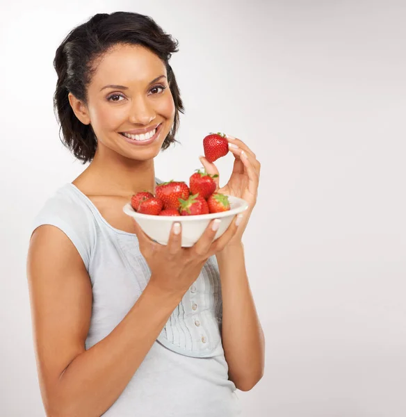 Dulce, jugoso y absolutamente delicioso. Retrato de una joven disfrutando de un tazón de fresas. — Foto de Stock