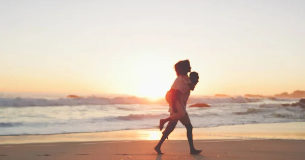 我们奔向夕阳。一对深情的年轻夫妇日落时在海滩散步的全景照片. — 图库照片