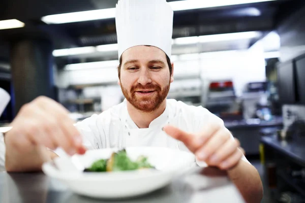 Lägger på finishen. Skott av en kock som lägger sista handen på en tallrik i ett professionellt kök. — Stockfoto