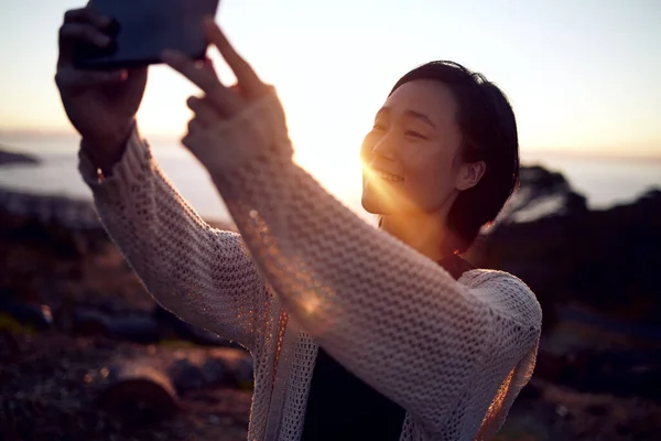 Algo sobre estar na natureza traz vibrações de selfie. Tiro de uma mulher tirando fotos em seu celular enquanto passa o tempo ao ar livre. — Fotografia de Stock
