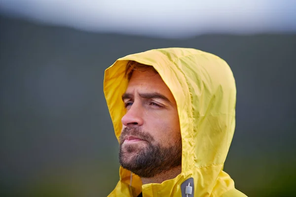 Imaginando sus objetivos de fitness. Tiro de un hombre de aspecto rugoso en equipo de lluvia amarilla al aire libre. — Foto de Stock