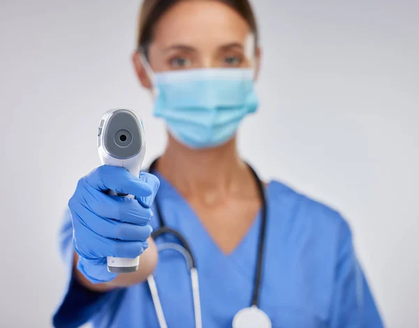 Πρέπει να ελέγξω τη θερμοκρασία σου. Φωτογραφία μιας νεαρής νοσοκόμας που κρατάει ψηφιακό θερμόμετρο σε φόντο στούντιο. — Φωτογραφία Αρχείου