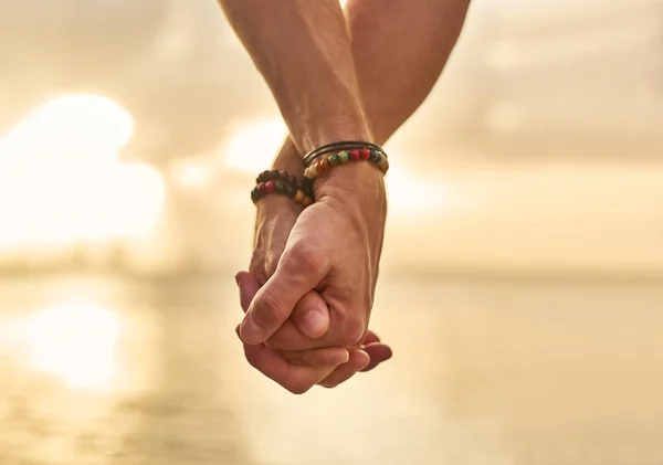 Segurando sua mão enquanto nos perguntamos a praia. close-up tiro de um casal irreconhecível de mãos dadas enquanto passar o dia na praia. — Fotografia de Stock
