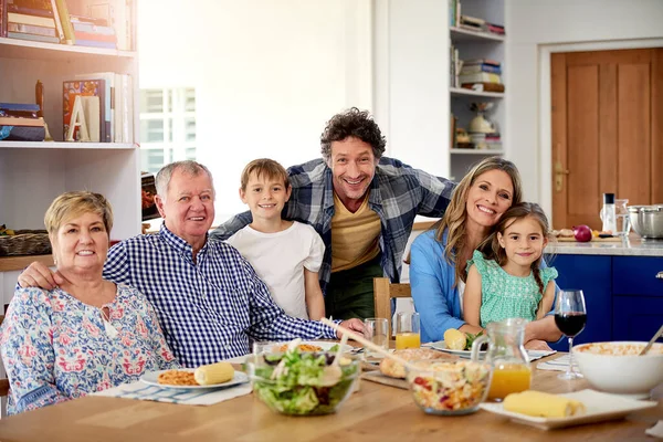 Goede tijden staan altijd op het menu bij familiebijeenkomsten. Portret van een multi-generationele familie genietend van een maaltijd samen thuis. — Stockfoto